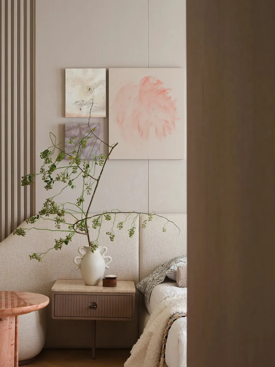 Minimalist bedroom featuring a textured nightstand and floral arrangement