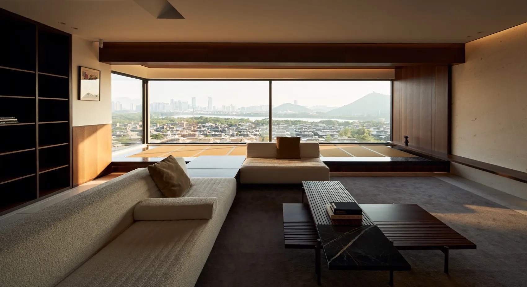 Modern living room featuring beige sofa and sectional with natural fiber upholstery, overlooking cityscape.
