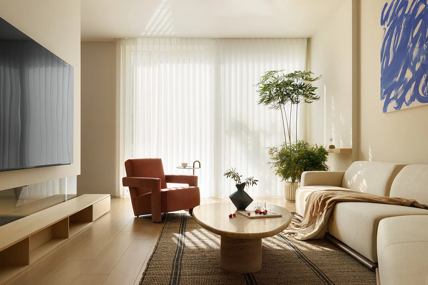 A modern living room with wooden flooring, fabric seating, glass vases, and concrete elements.