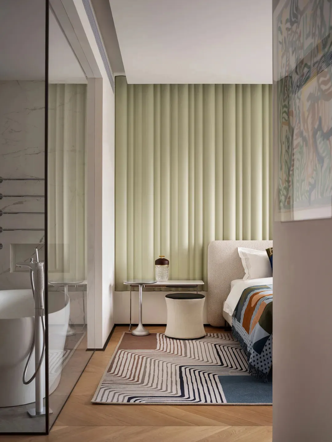 A modern, minimalist bedroom interior with a large bed, colorful bedding, and contemporary furniture.