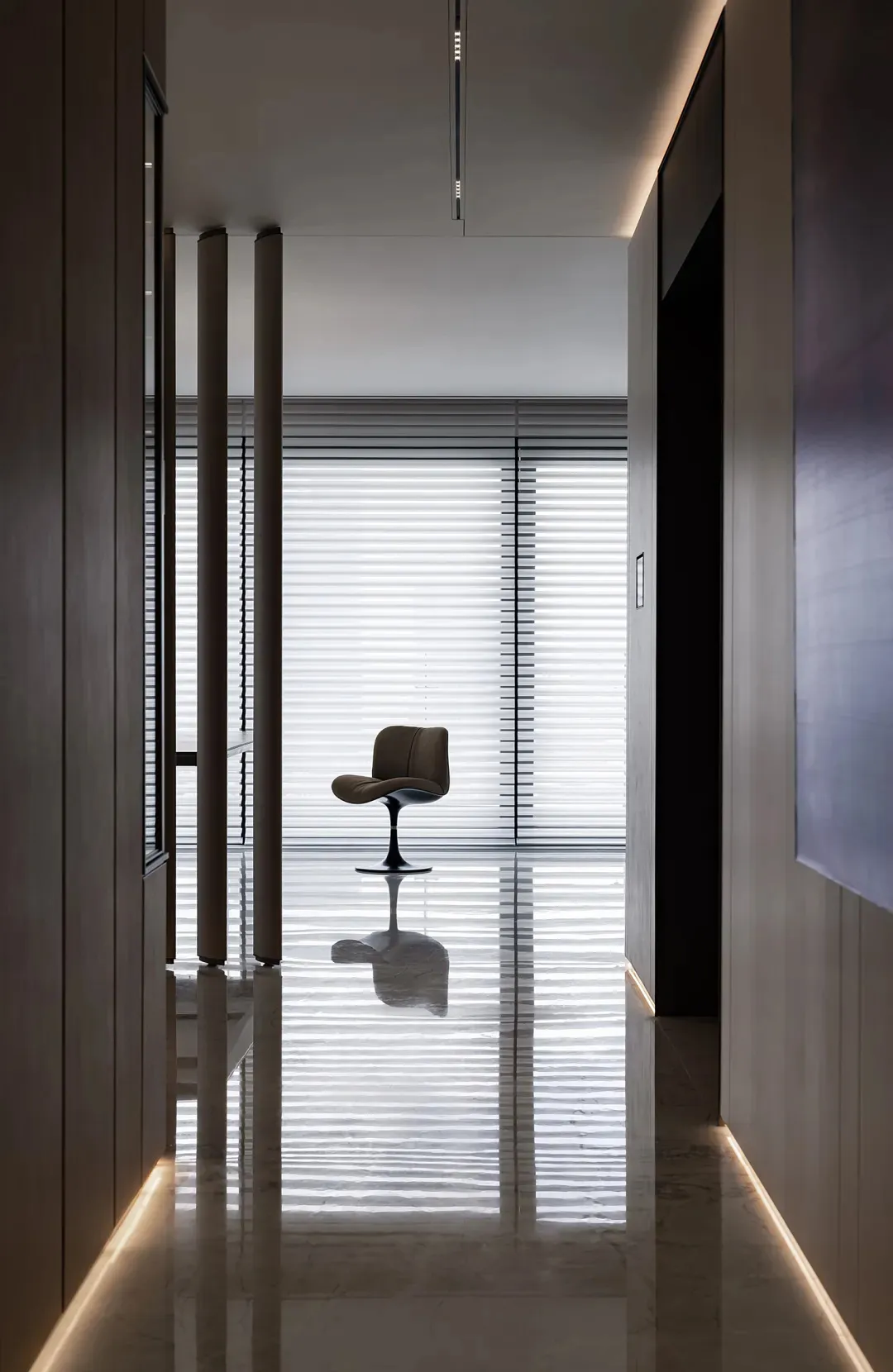 A minimalist office with a glass window and a single chair reflected in the glossy floor.