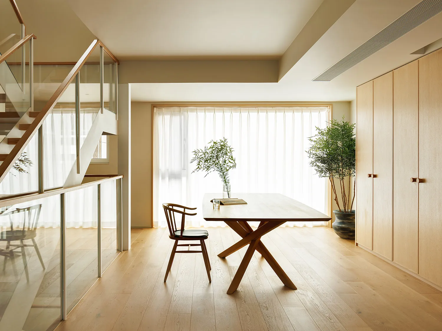 A minimalist living room with wooden furniture and a large window.