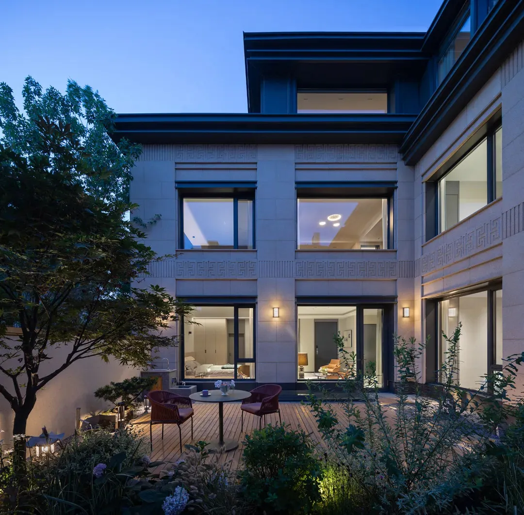 A modern house with concrete exterior walls at dusk with a lit patio area.
