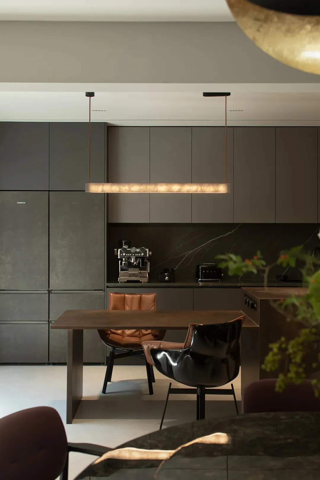A modern kitchen with marble countertops and cabinets, featuring a dining table and chairs.