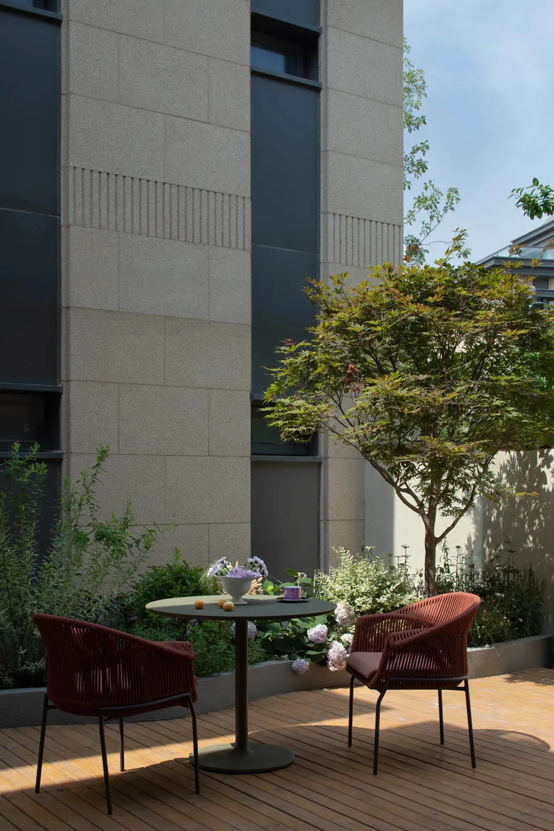 Modern outdoor space featuring a serene tropical deck with plants, wood, and concrete materials.