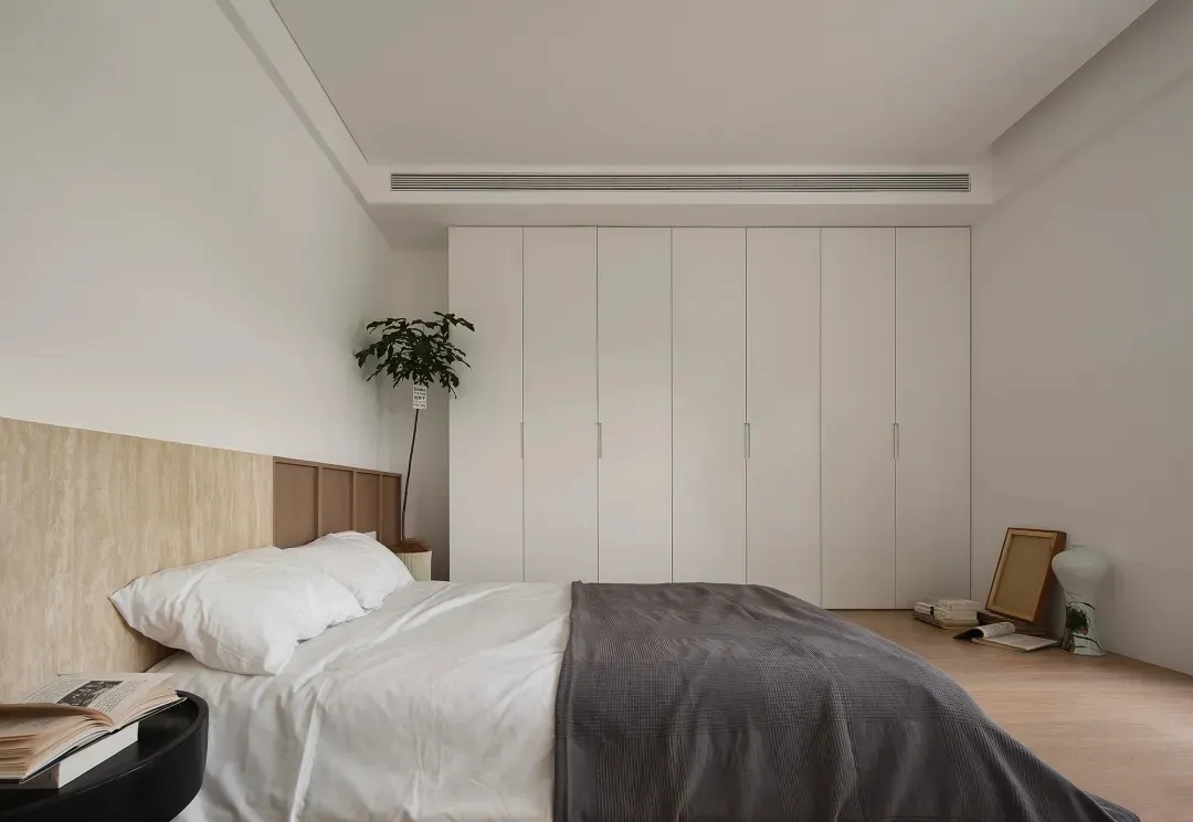 Minimalist bedroom with neutral materials and a large wardrobe.