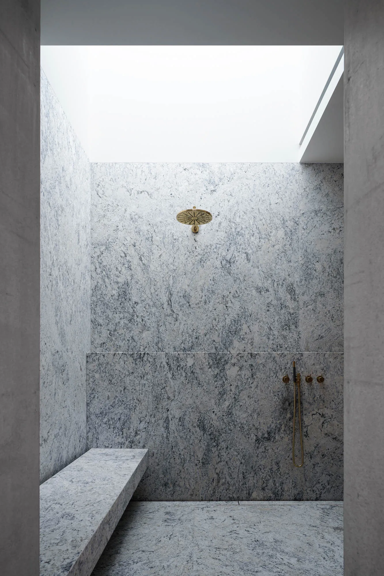 Modern bathroom featuring granite walls and marble shower bench