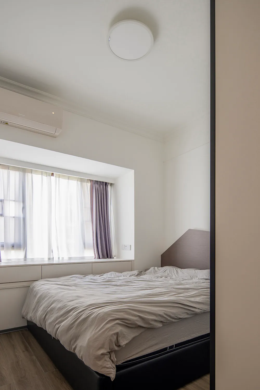 A minimalist bedroom with a bed, curtains, and a ceiling light fixture.