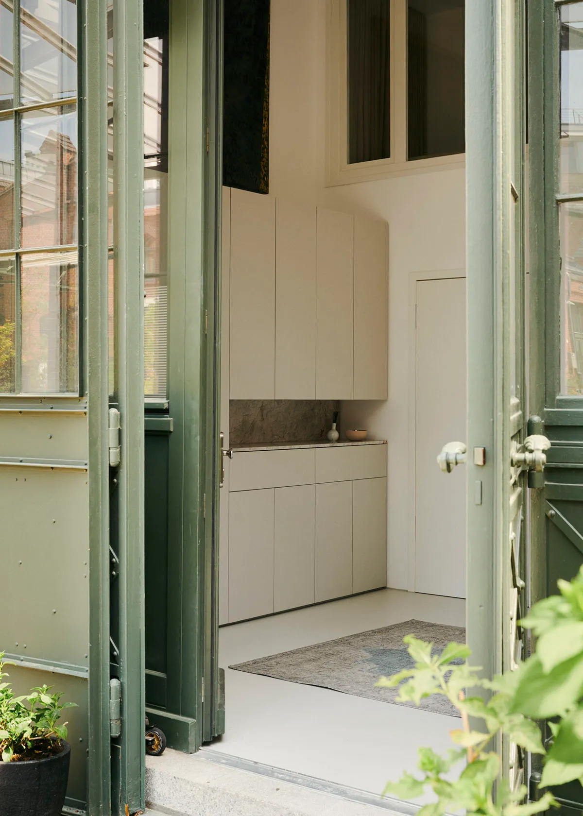 A modern apartment entryway featuring white walls, doors, and cabinets.