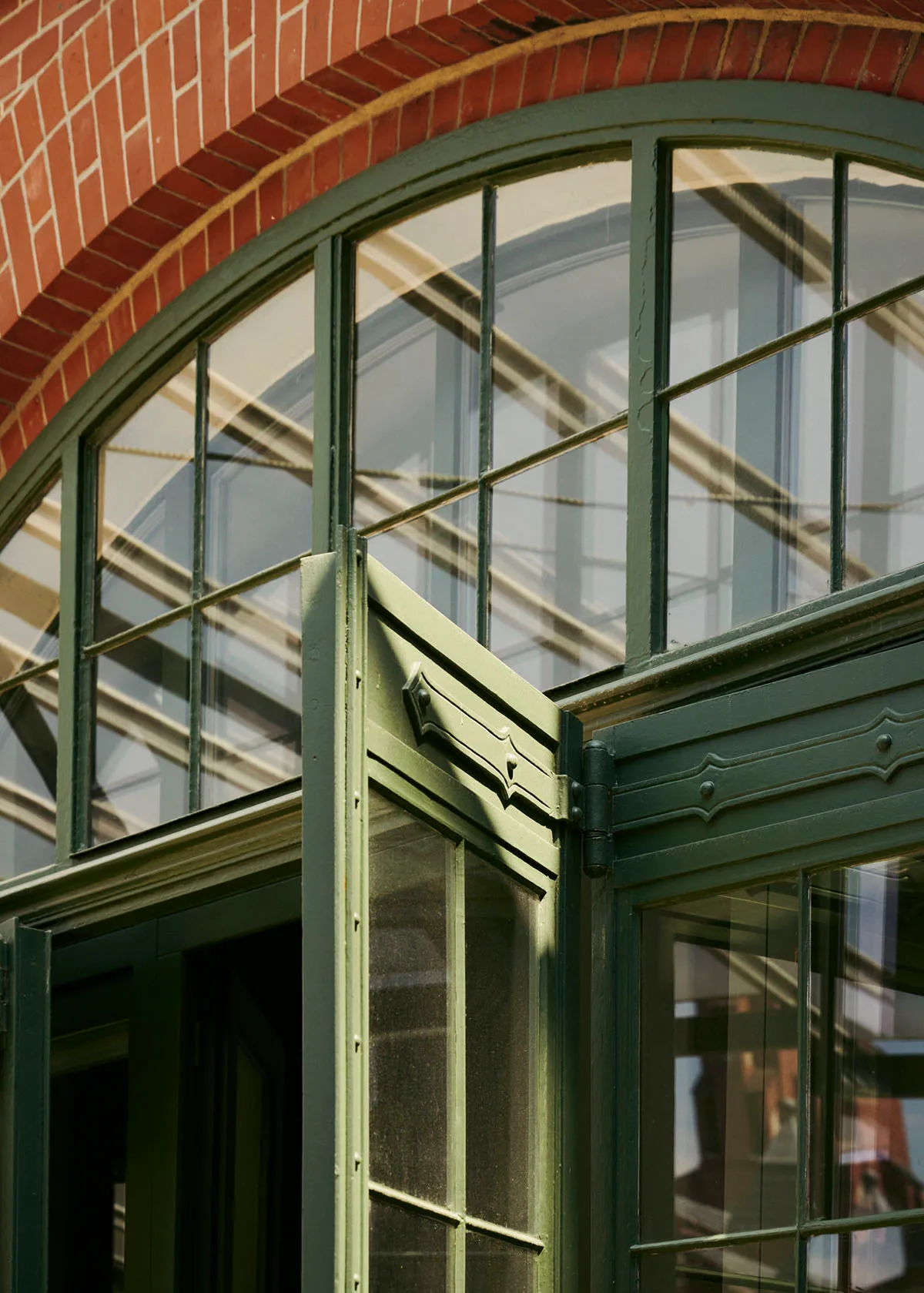 Modern building exterior featuring large glass windows with green frames.