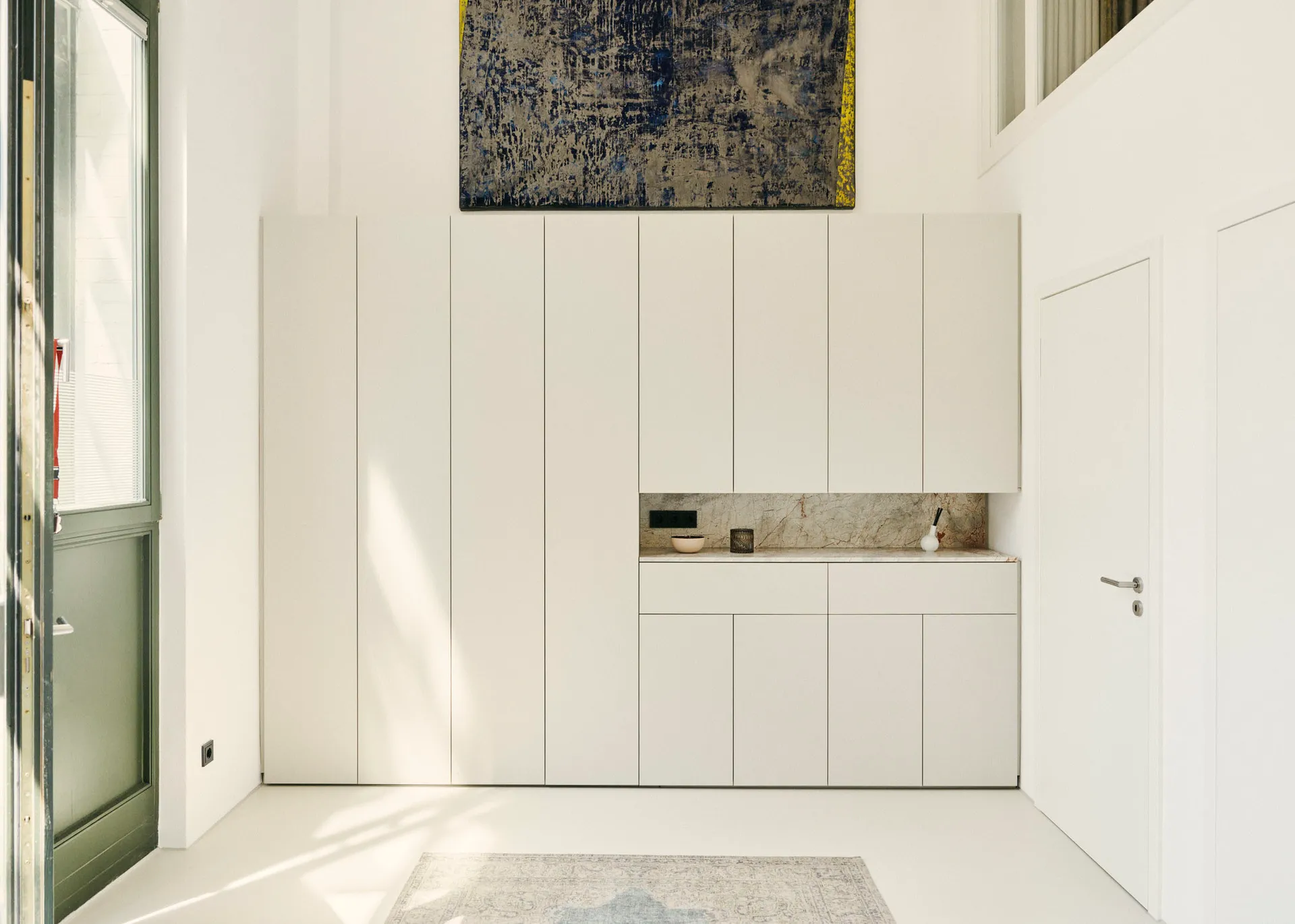 Modern minimalist kitchen with white cabinets and marble countertops and backsplash.