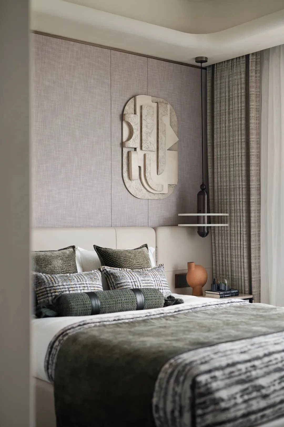 Modern bedroom featuring a bed with textured cushions and a textured wall panel.