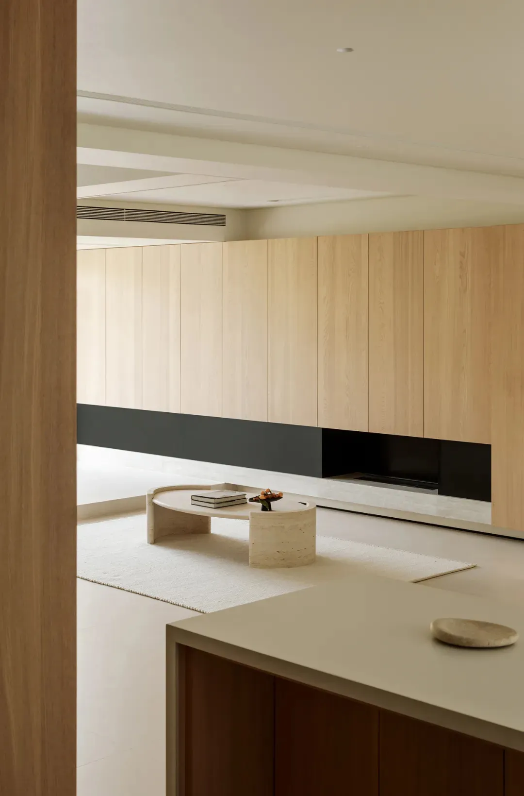 A minimalist residential interior designed with wooden and marble elements.