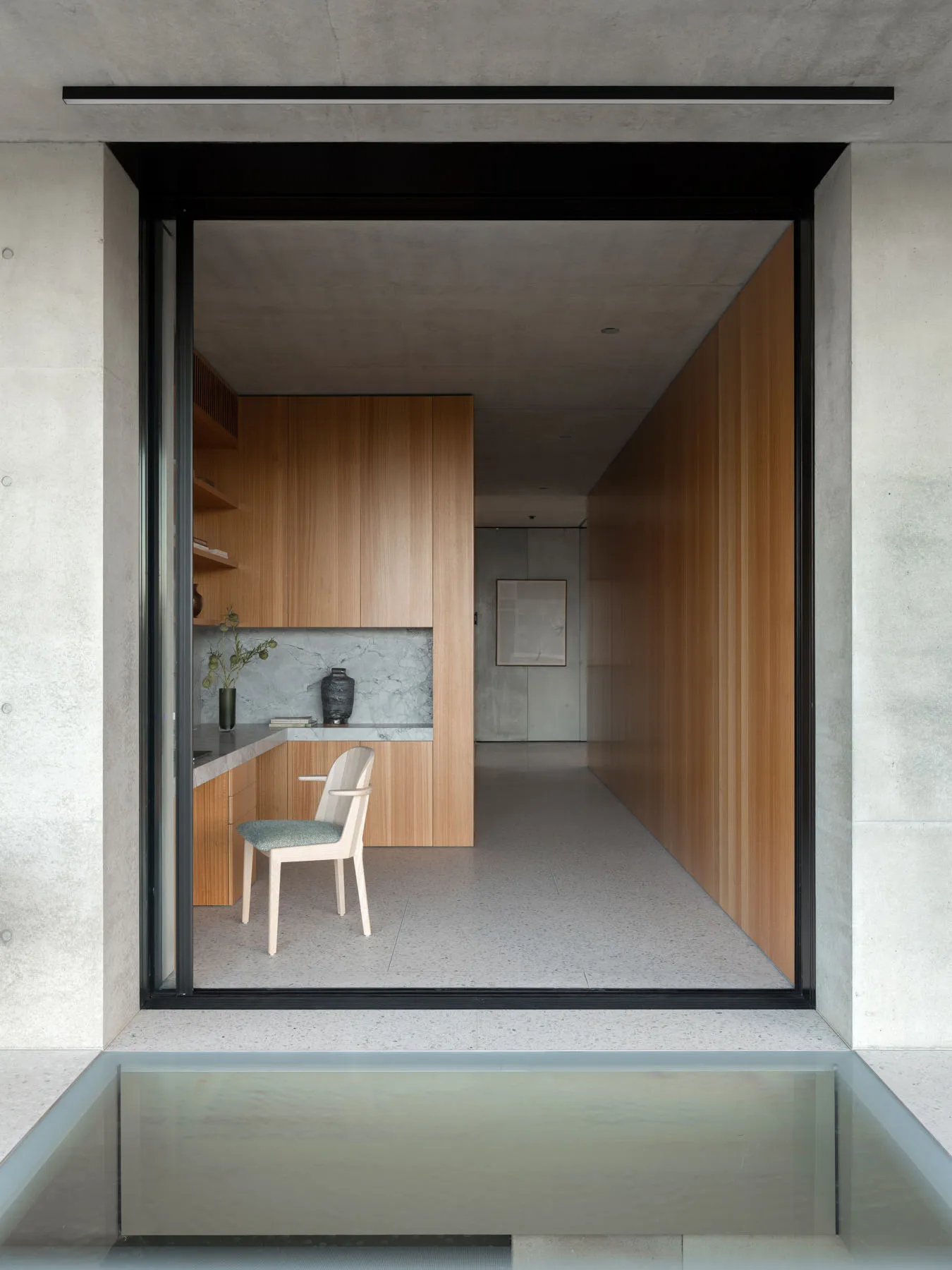 A minimalist kitchen featuring wooden cabinets and marble countertops.