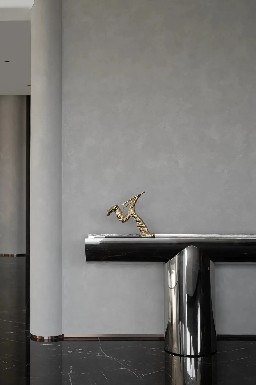 A sleek, modern console table with a brass sculpture in a minimalist interior setting.
