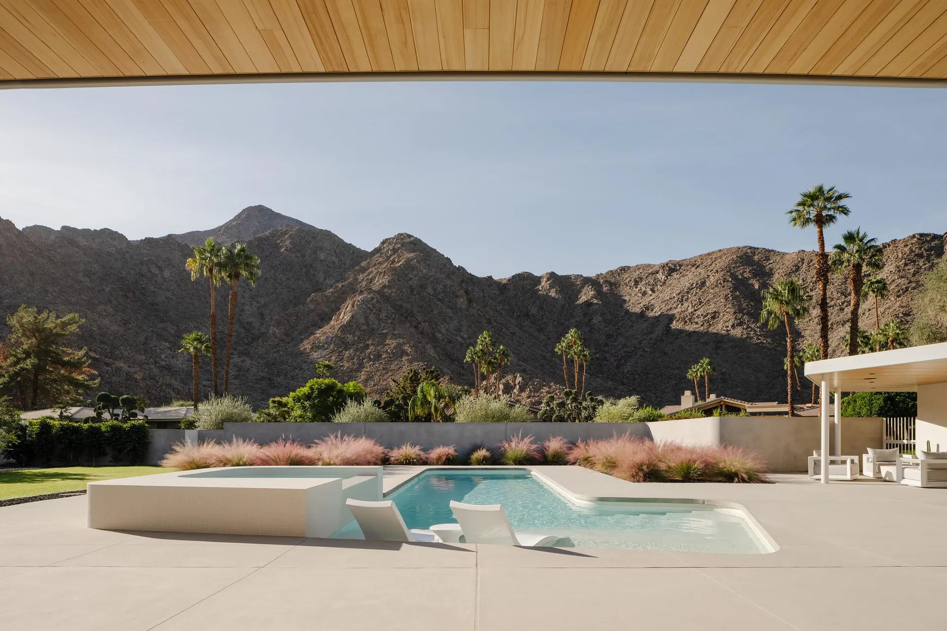 Modern residential outdoor space featuring a swimming pool, mountain view, and landscaping.