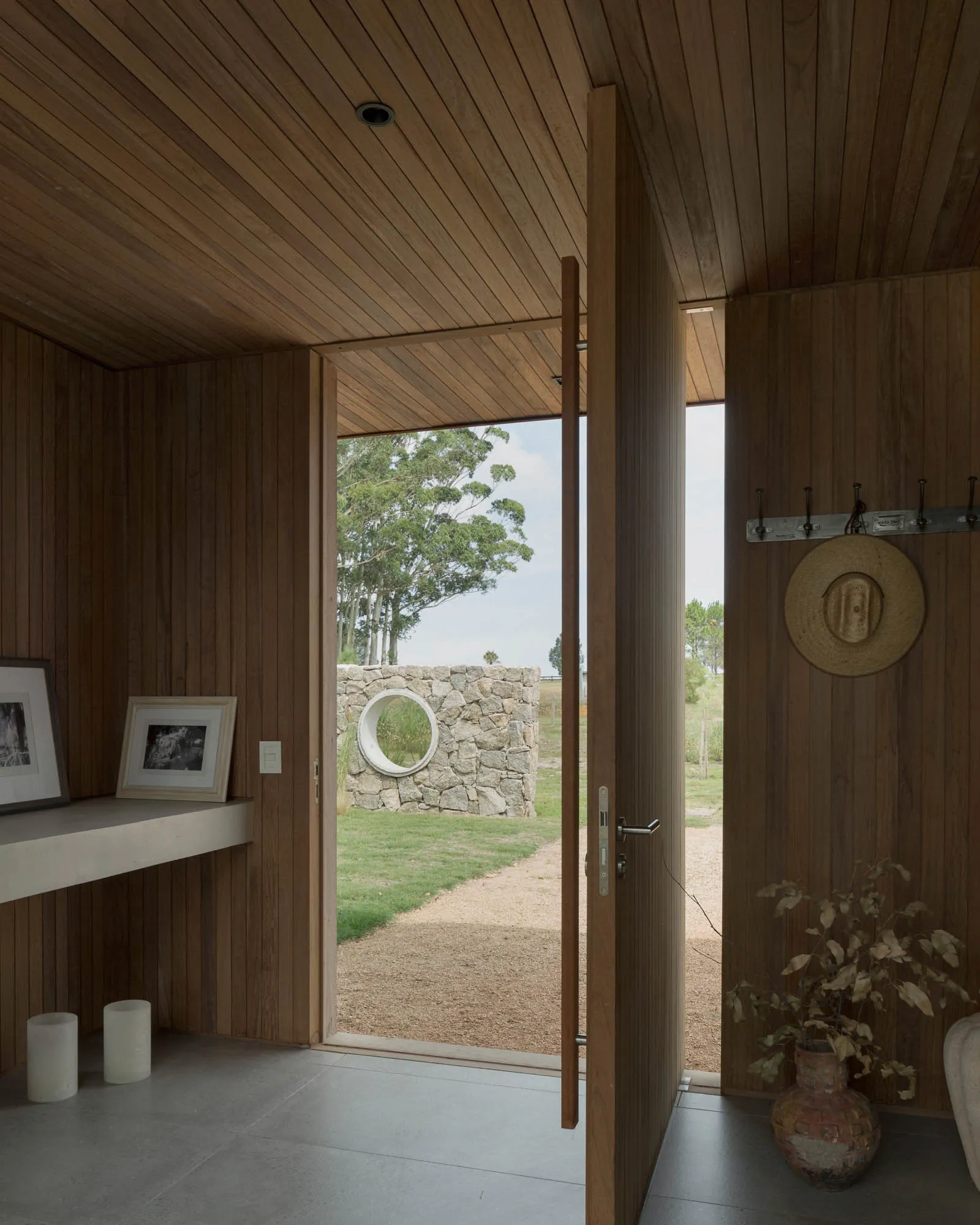 An entrance with wooden panels and a view of the outdoors through an open door.
