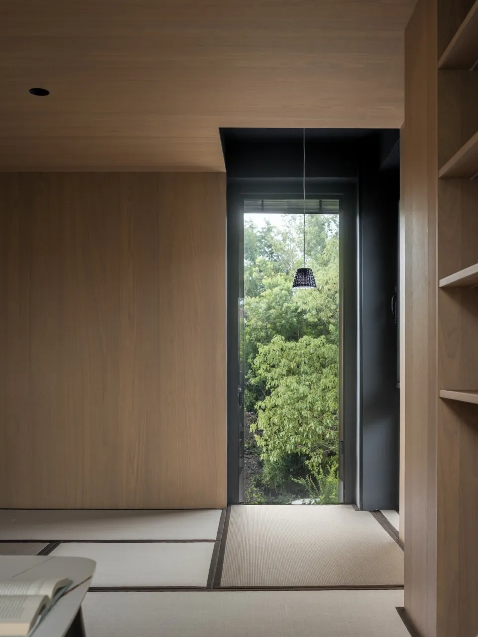 A minimalist interior design with wooden timber tiles and green plants, featuring a door leading to an outdoor area with gree