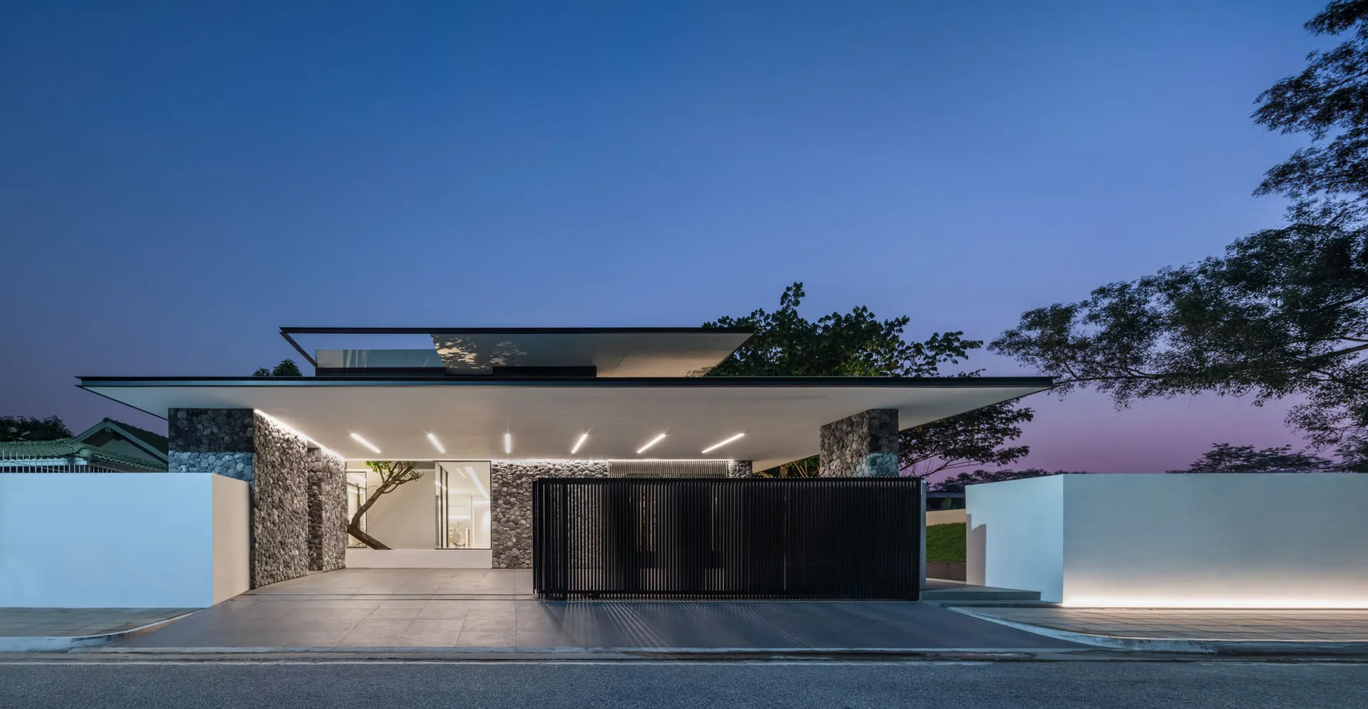 A modern house with a concrete exterior, glass rooftop, and stone accents.