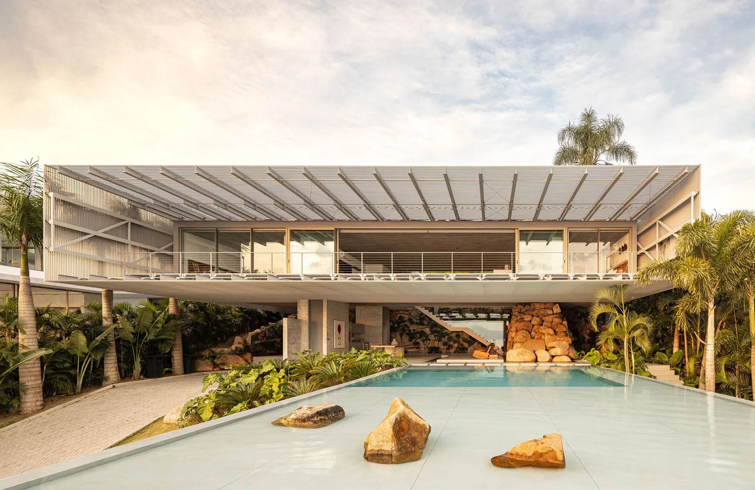A modern residential house featuring a glass and concrete exterior with metal accents.
