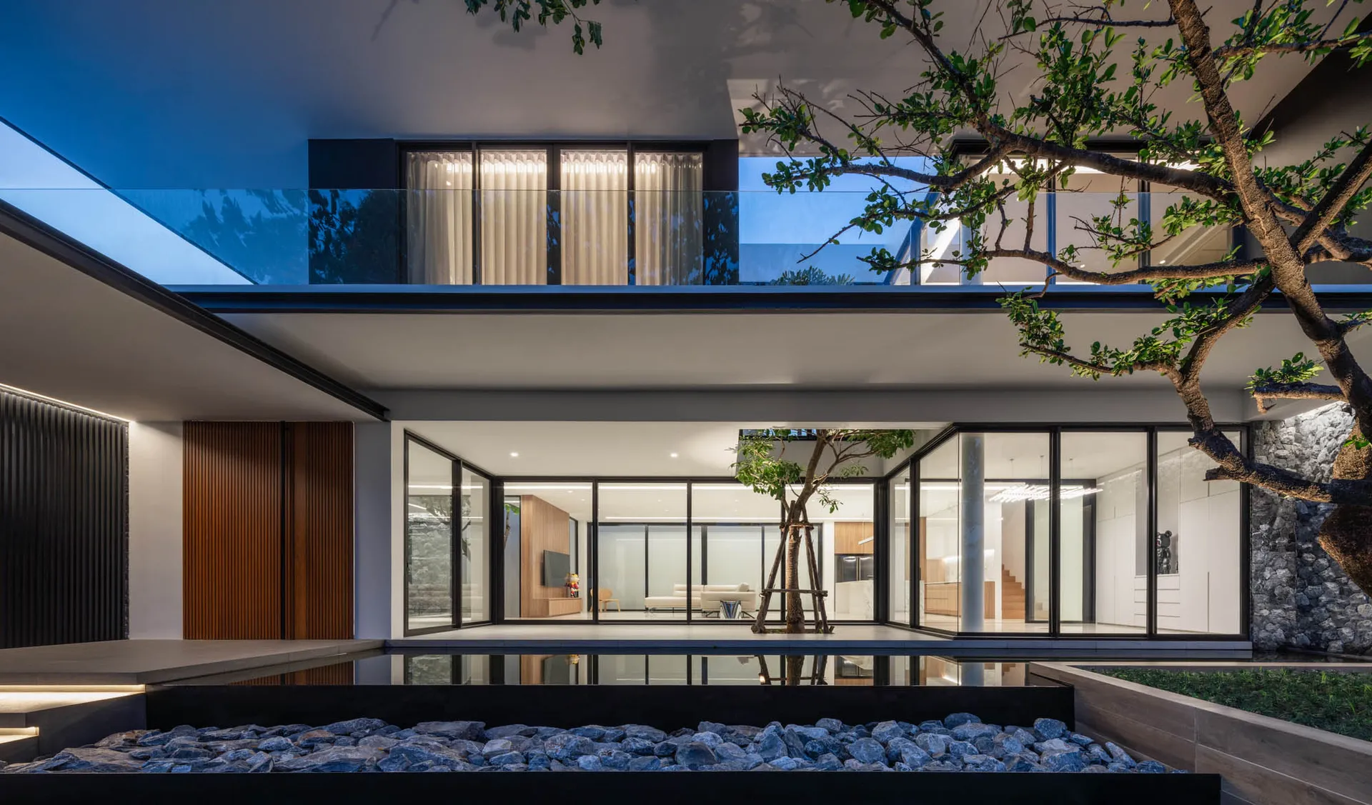 Modern residential interior with glass walls, wood flooring, and concrete patio.