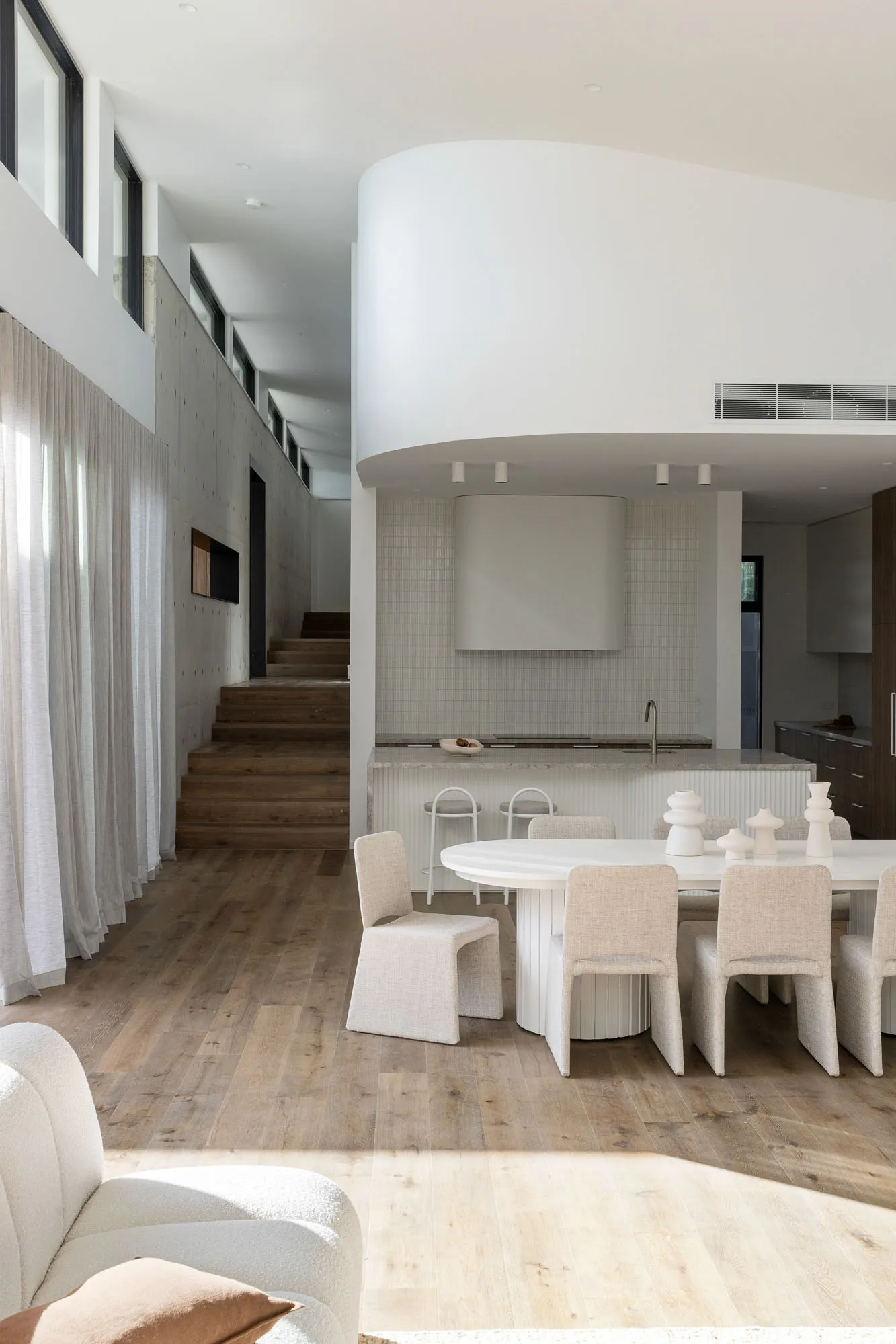 A modern minimalist interior featuring wooden floors, concrete walls, and fabric upholstered furniture.