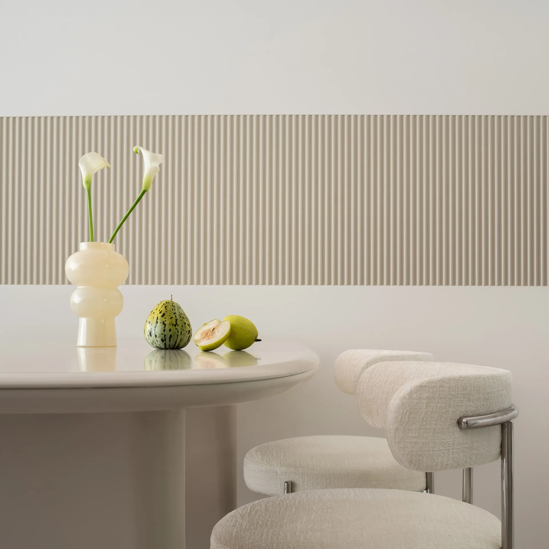 A minimalist white interior design with a white table, chairs, and a vase of white flowers, featuring textured white wall pan