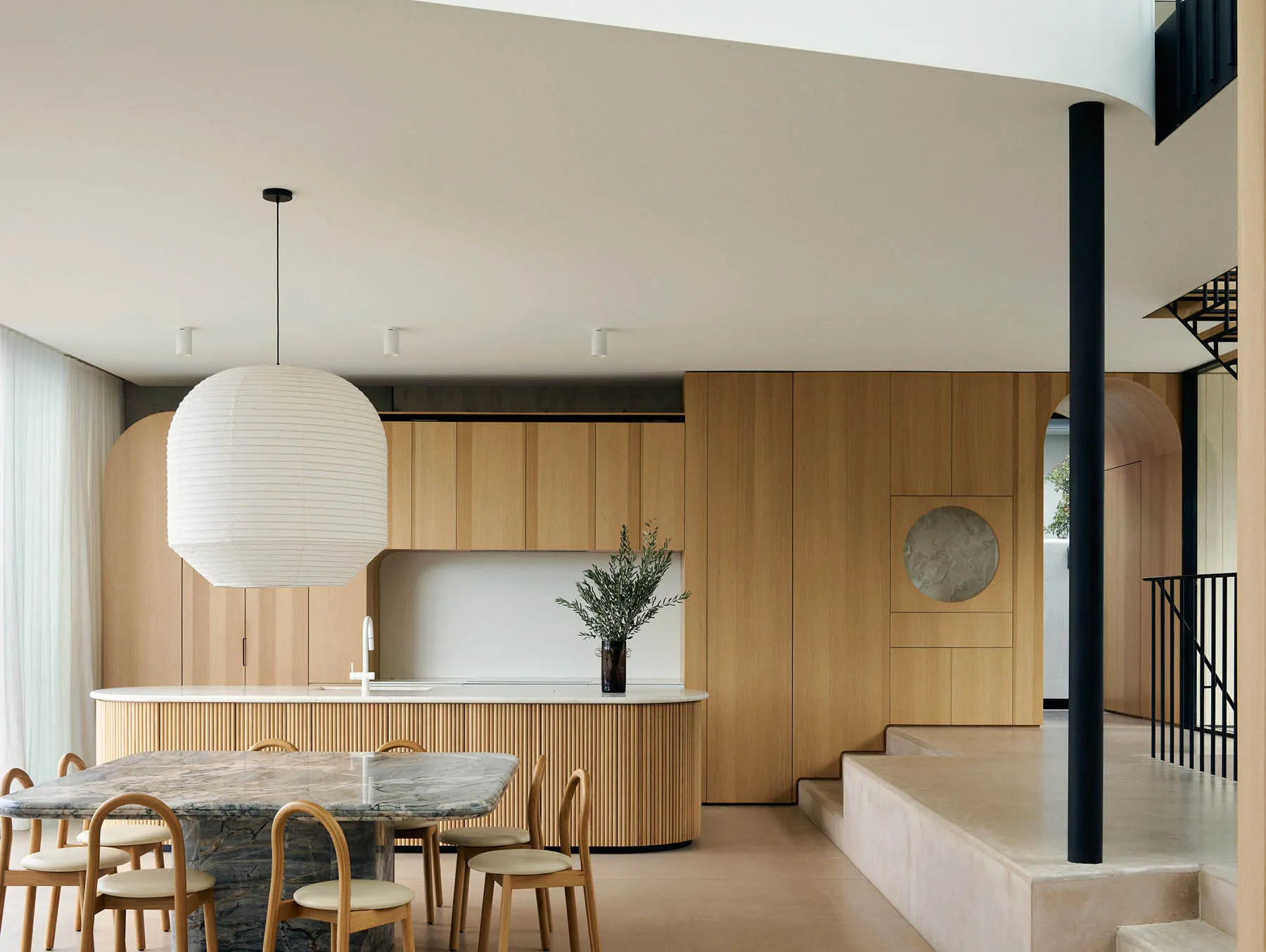 Modern minimalist kitchen with wooden cabinets and a marble dining table and chairs.