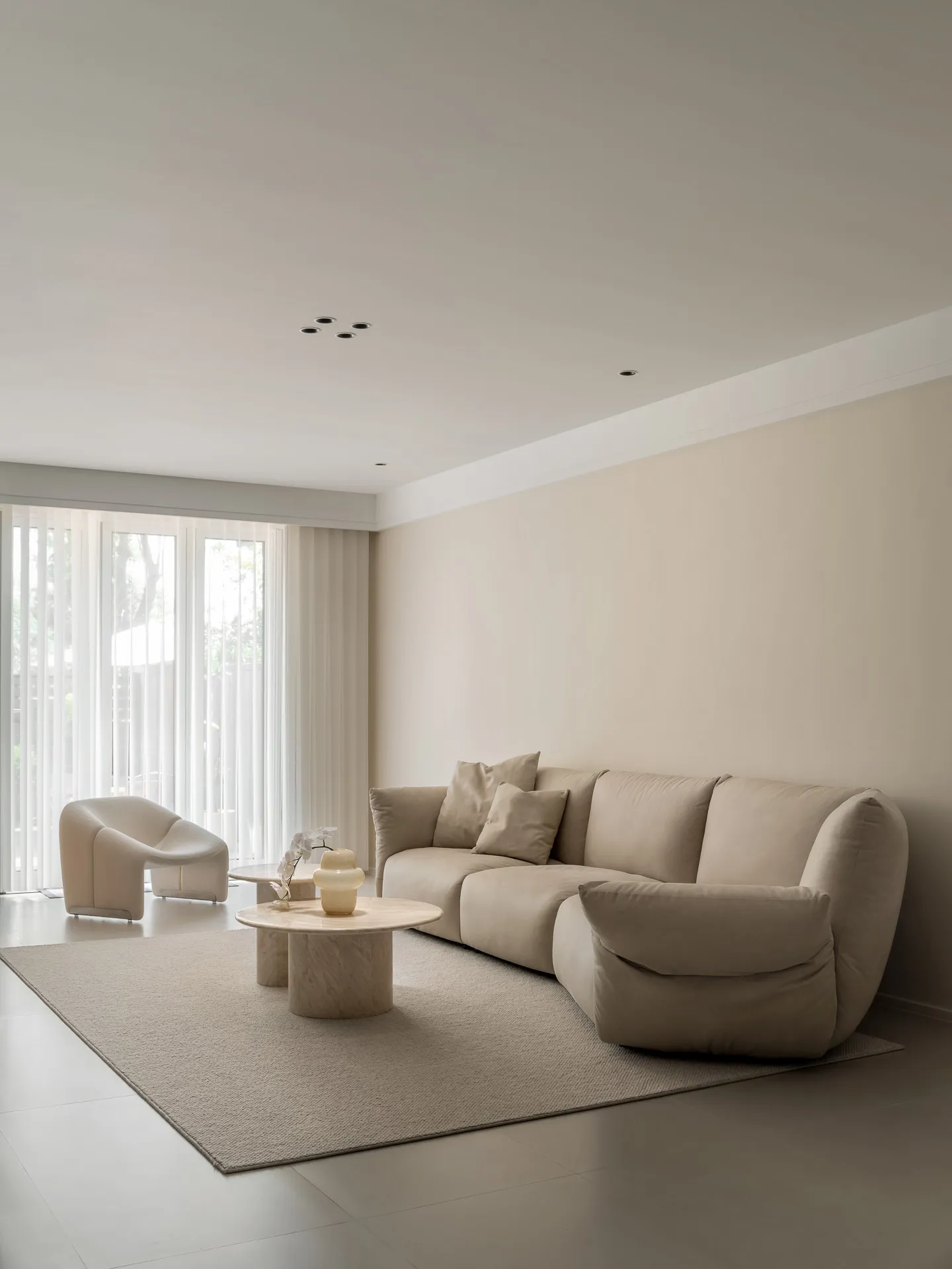 A minimalist living room with neutral colors, featuring a comfortable sofa, accent chair, and round coffee table.