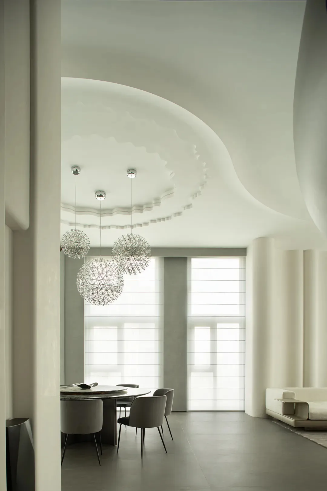 A minimalist dining room featuring textured concrete walls and ceiling.