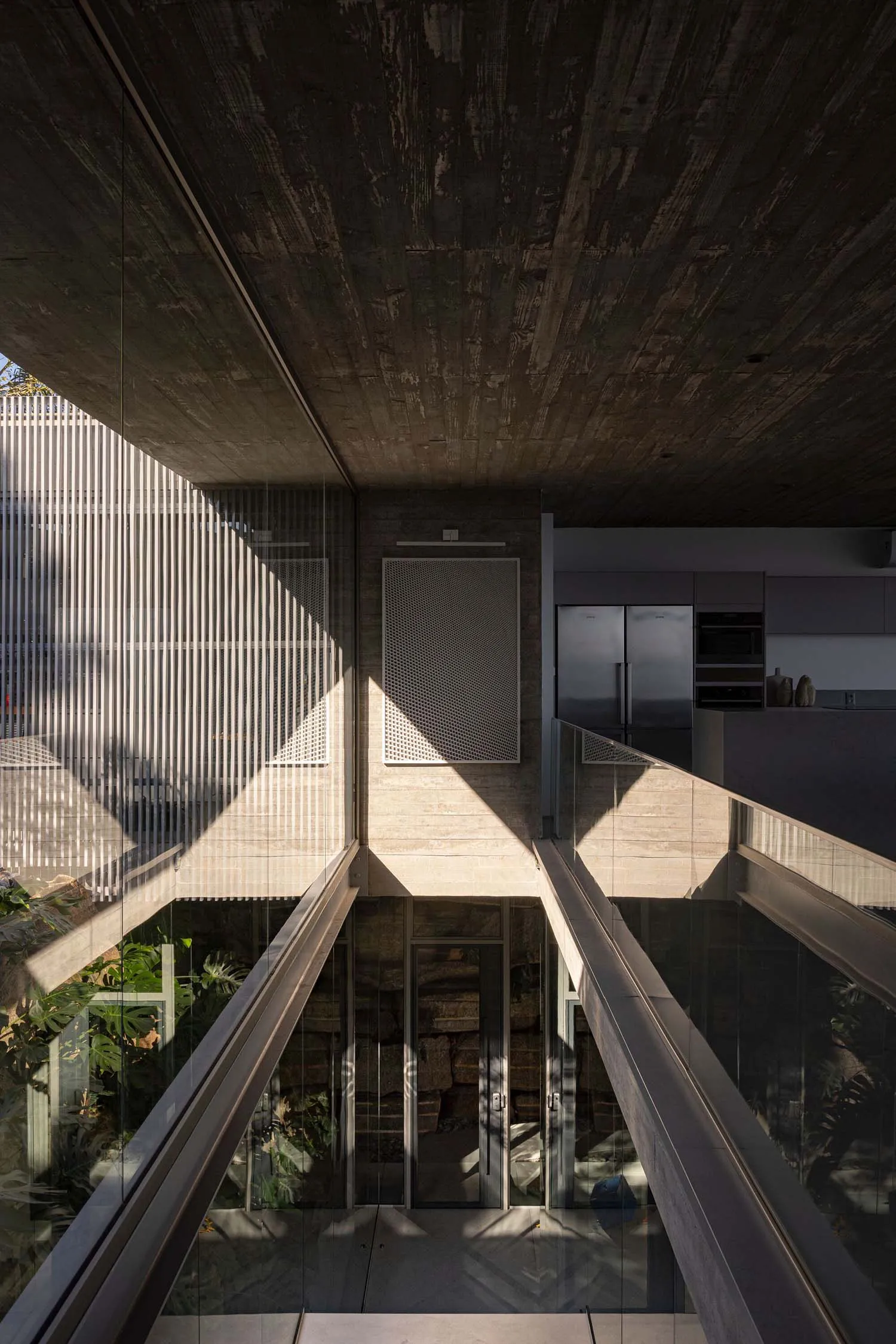 A futuristic industrial-style residential kitchen designed with concrete and glass materials, featuring a sleek, modern aesth