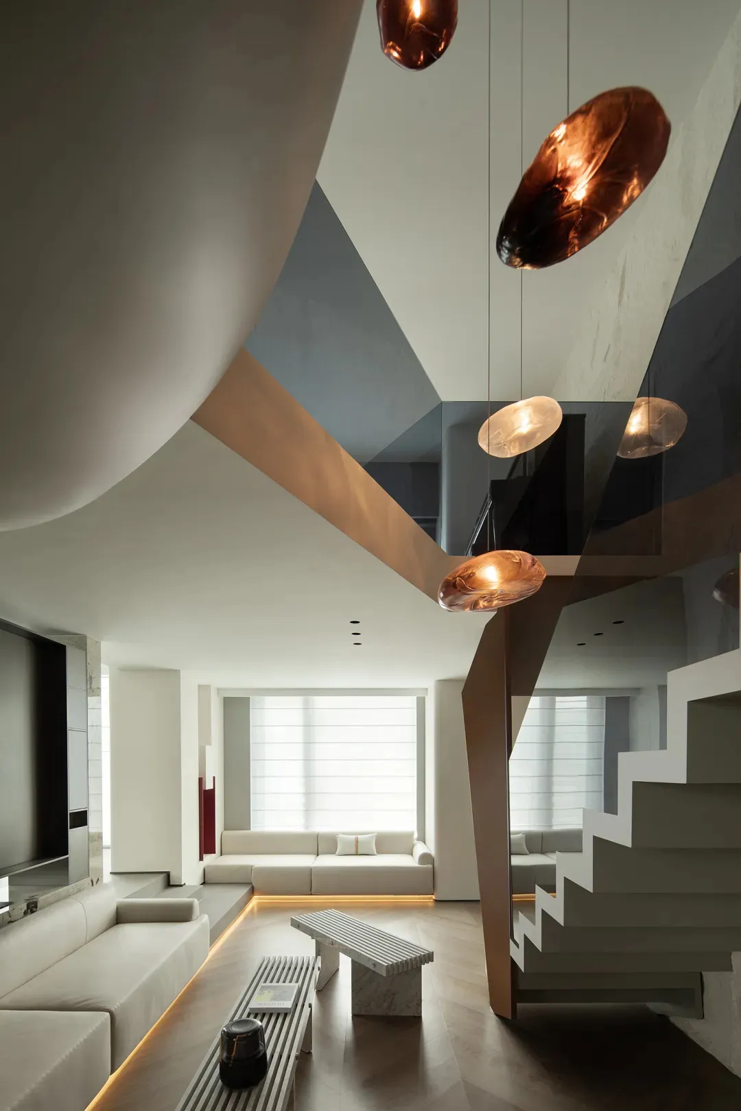 A minimalist modern living room featuring exposed concrete walls and floor, with a built-in curved sofa, glass pendant lights