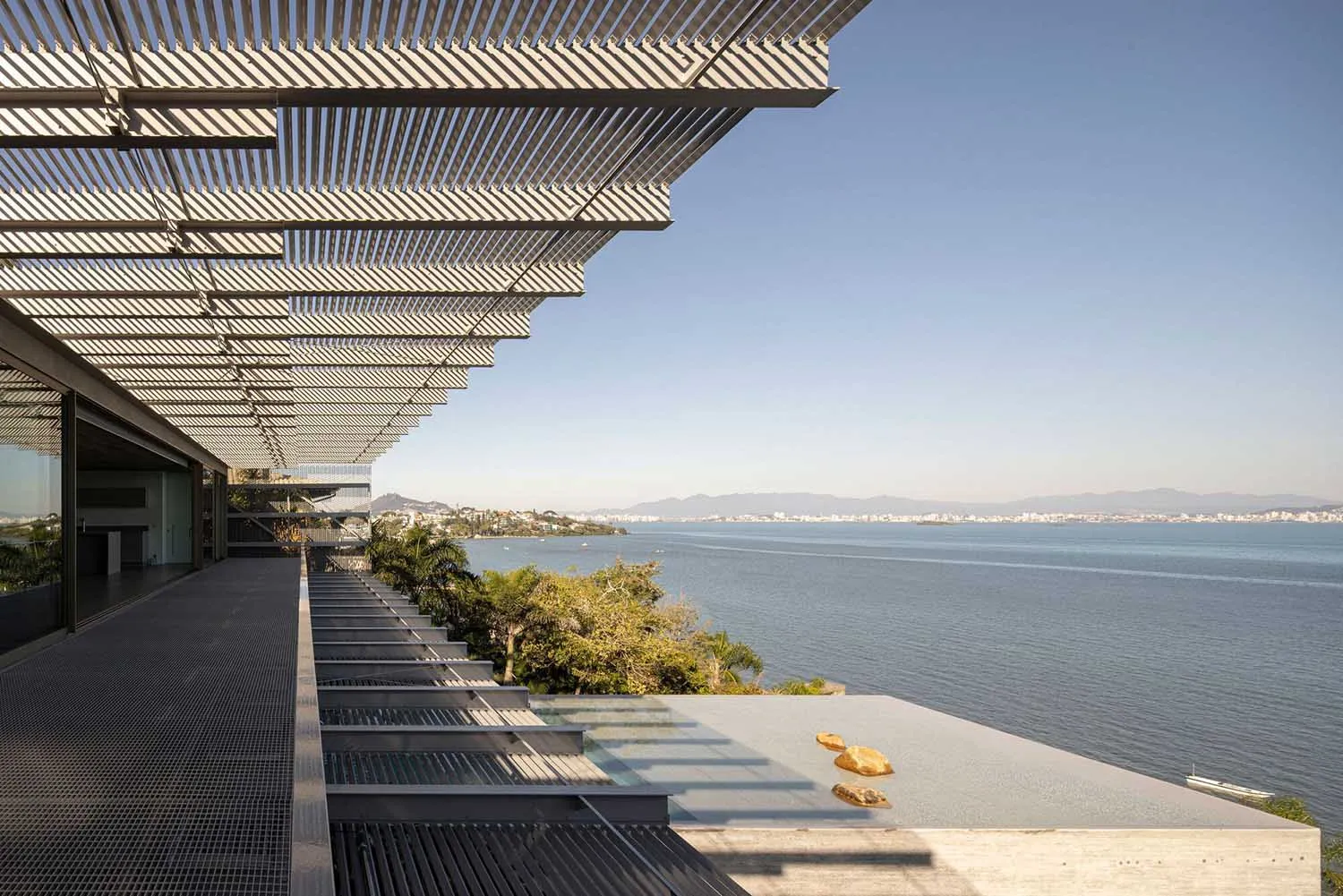 A modern residential interior with a concrete poolside overlooking the ocean.