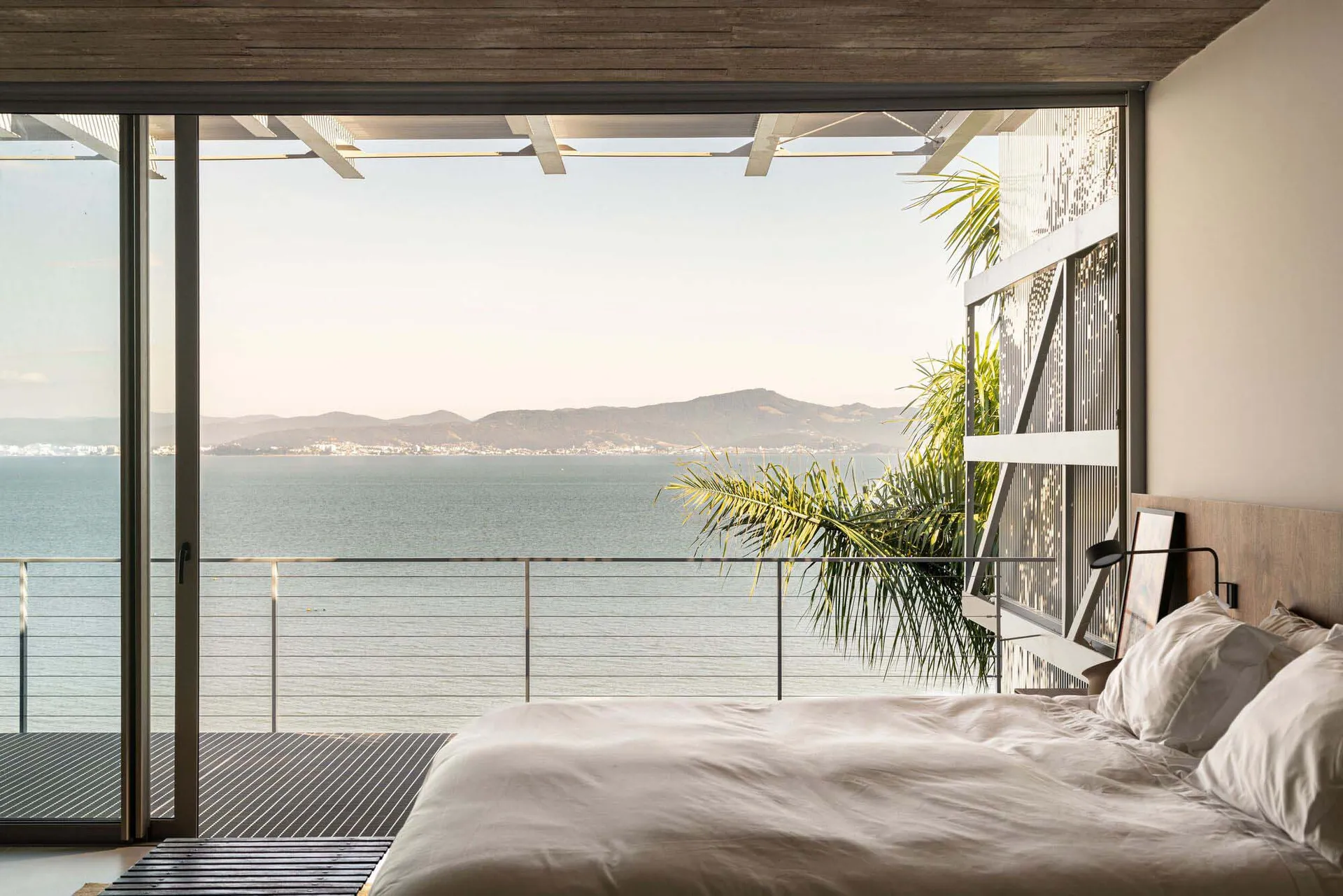 Modern bedroom overlooking the ocean with a king-sized bed and minimalistic design.