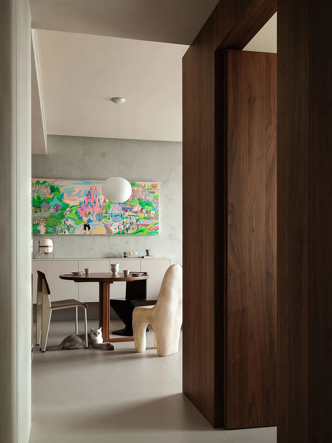 Modern dining room with a wooden table, concrete wall, and fabric chairs.