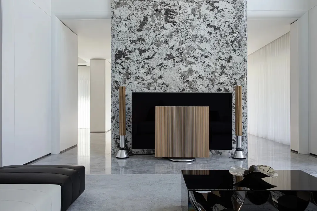 A minimalist living room with marble walls and a black coffee table.