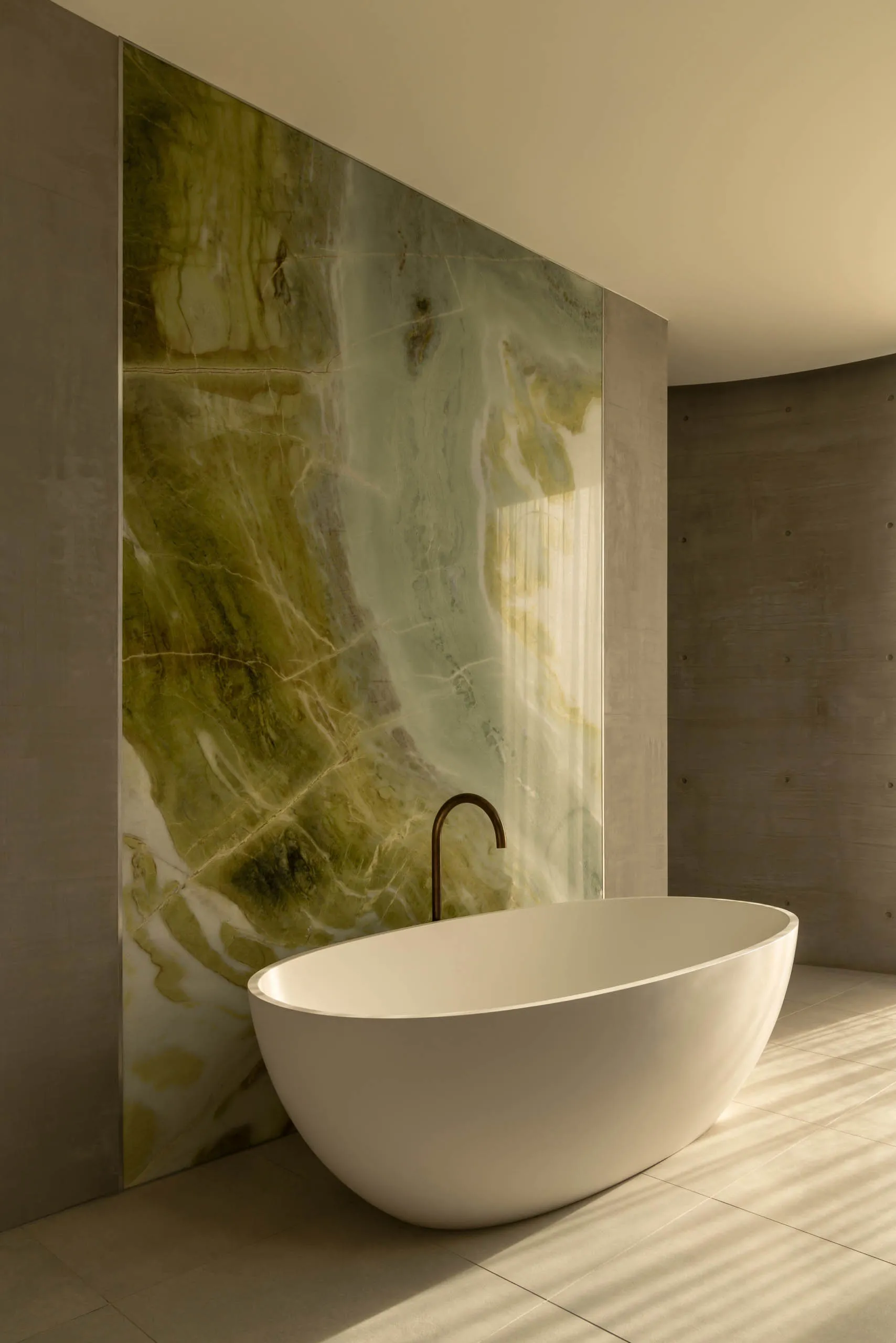 Modern bathroom interior featuring a freestanding bathtub with a polished marble backdrop.