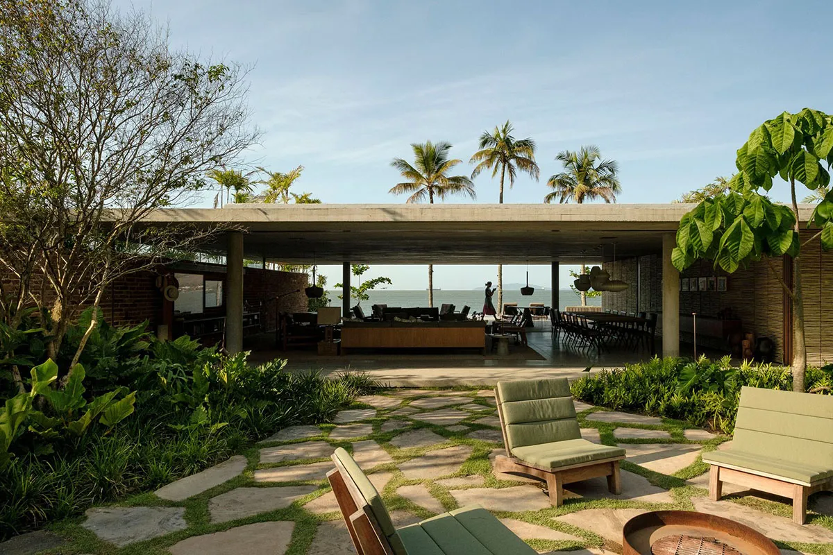 A modern residential patio featuring stone floors, wooden furniture, and concrete structures.