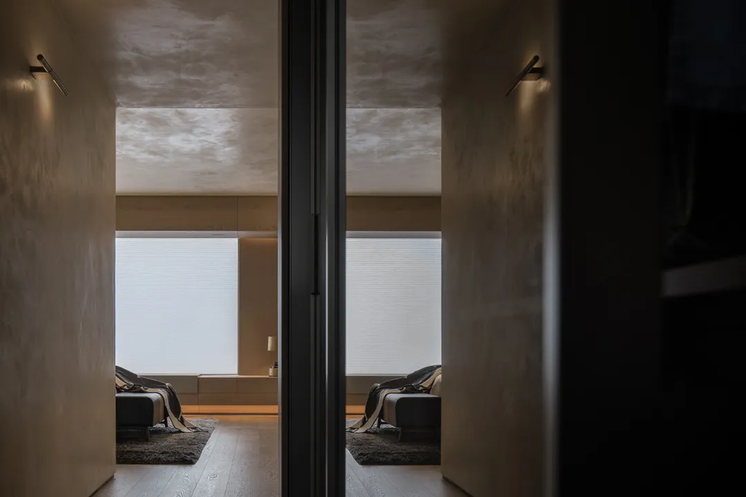 A minimalist bedroom with wooden flooring and furniture.