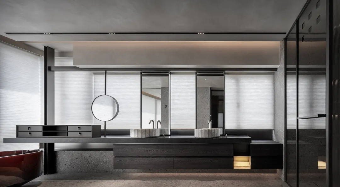 Modern bathroom interior with black concrete floor and walls, featuring a double vanity with marble countertops and sinks.