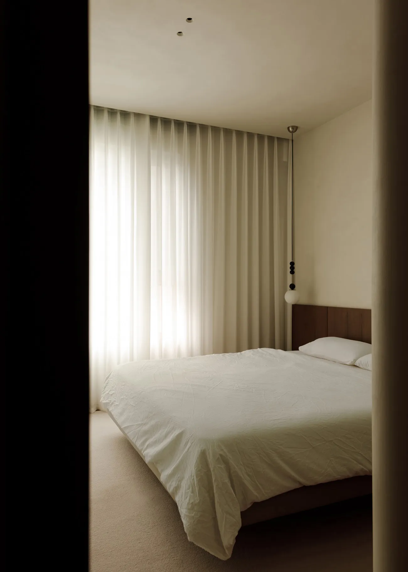 An image of a modern bedroom featuring fabric bedding, a wooden headboard, and a glass window.