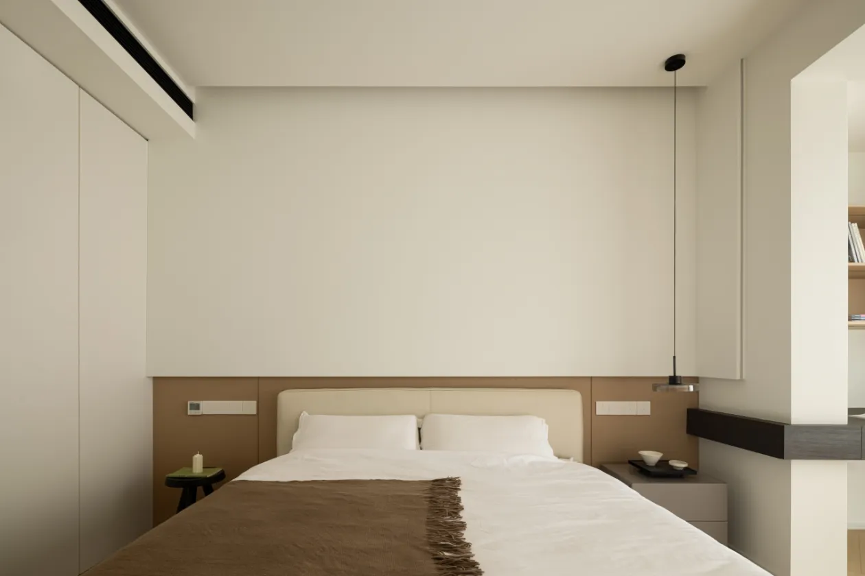 A minimalist bedroom with a bed, nightstands, and a hanging light fixture.