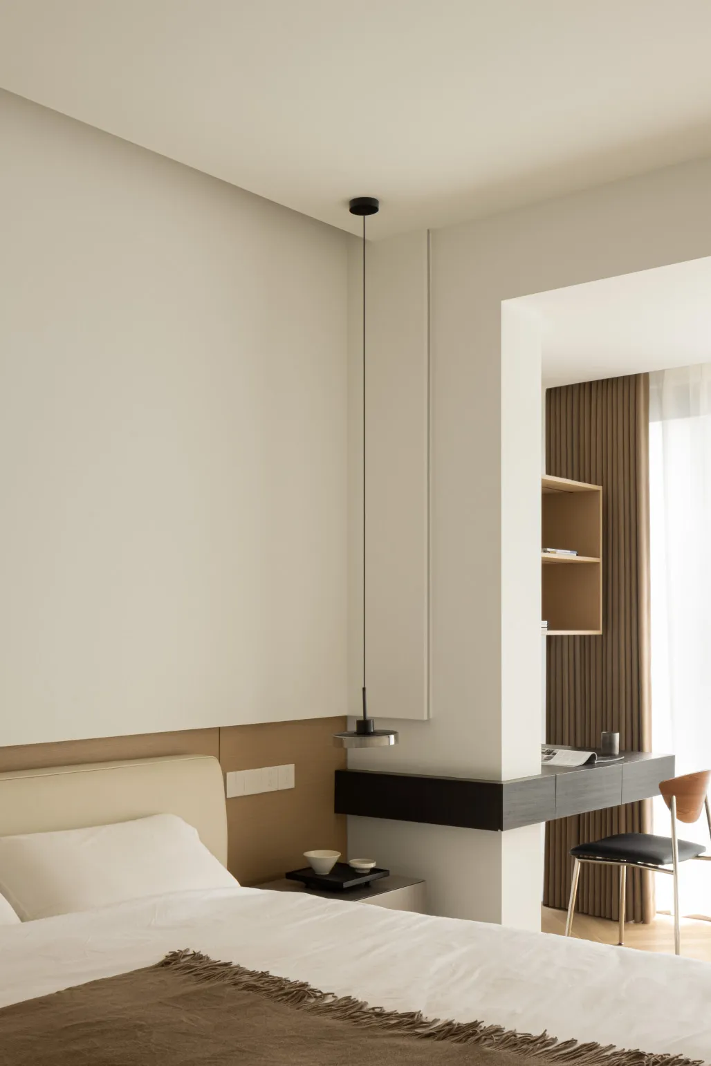 Modern minimalist bedroom with white walls and simple furniture.