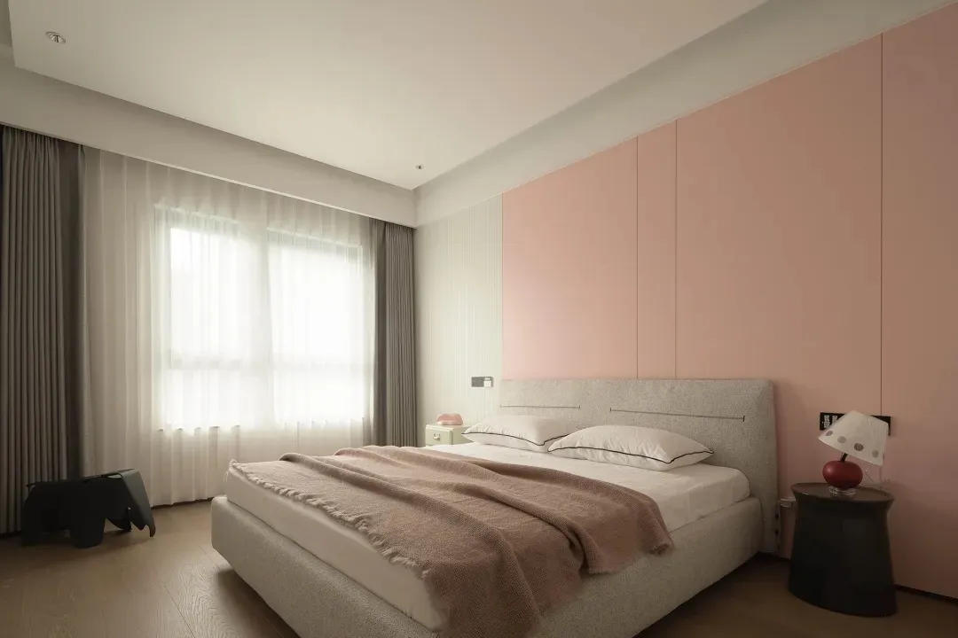 Minimalist bedroom with white walls, pink accent wall, and textured material headboard.