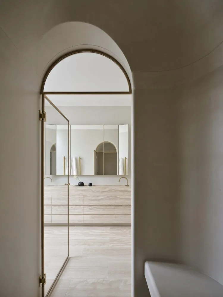 Modern, minimalist bathroom with marble walls and gold accents.
