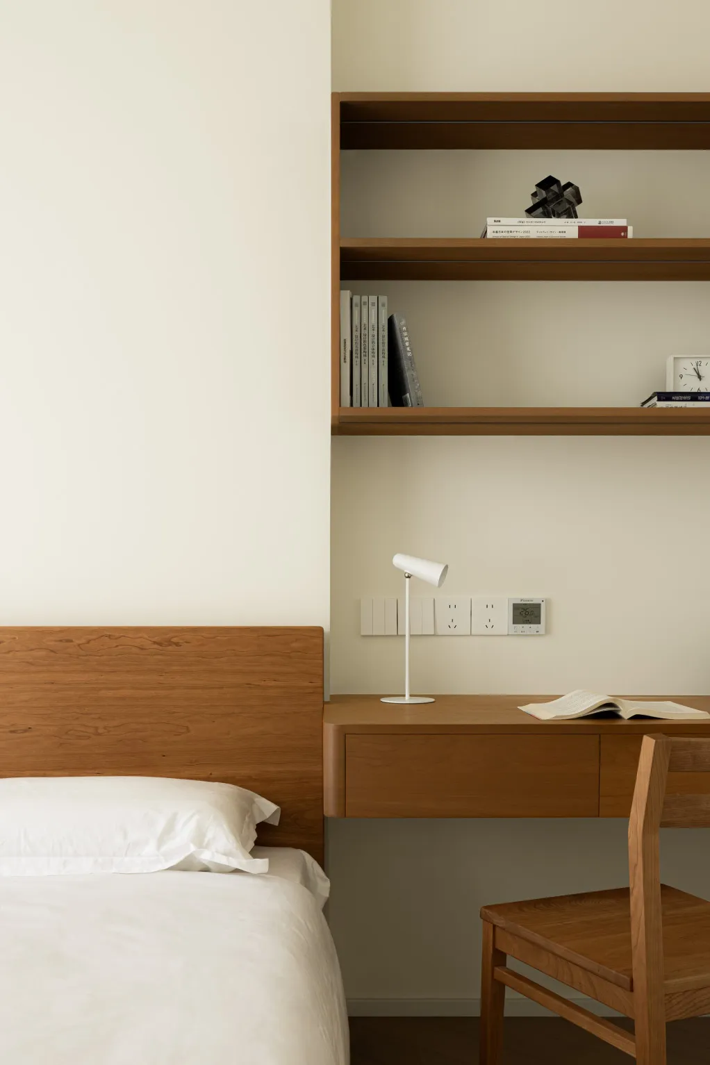 Minimalist bedroom with wooden furniture and white bedding.