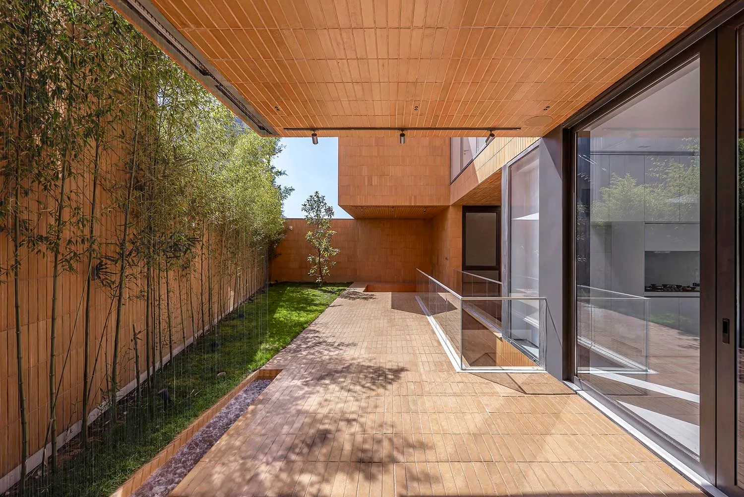 A modern residential space featuring wooden interiors and exteriors with a greenery-lined courtyard.