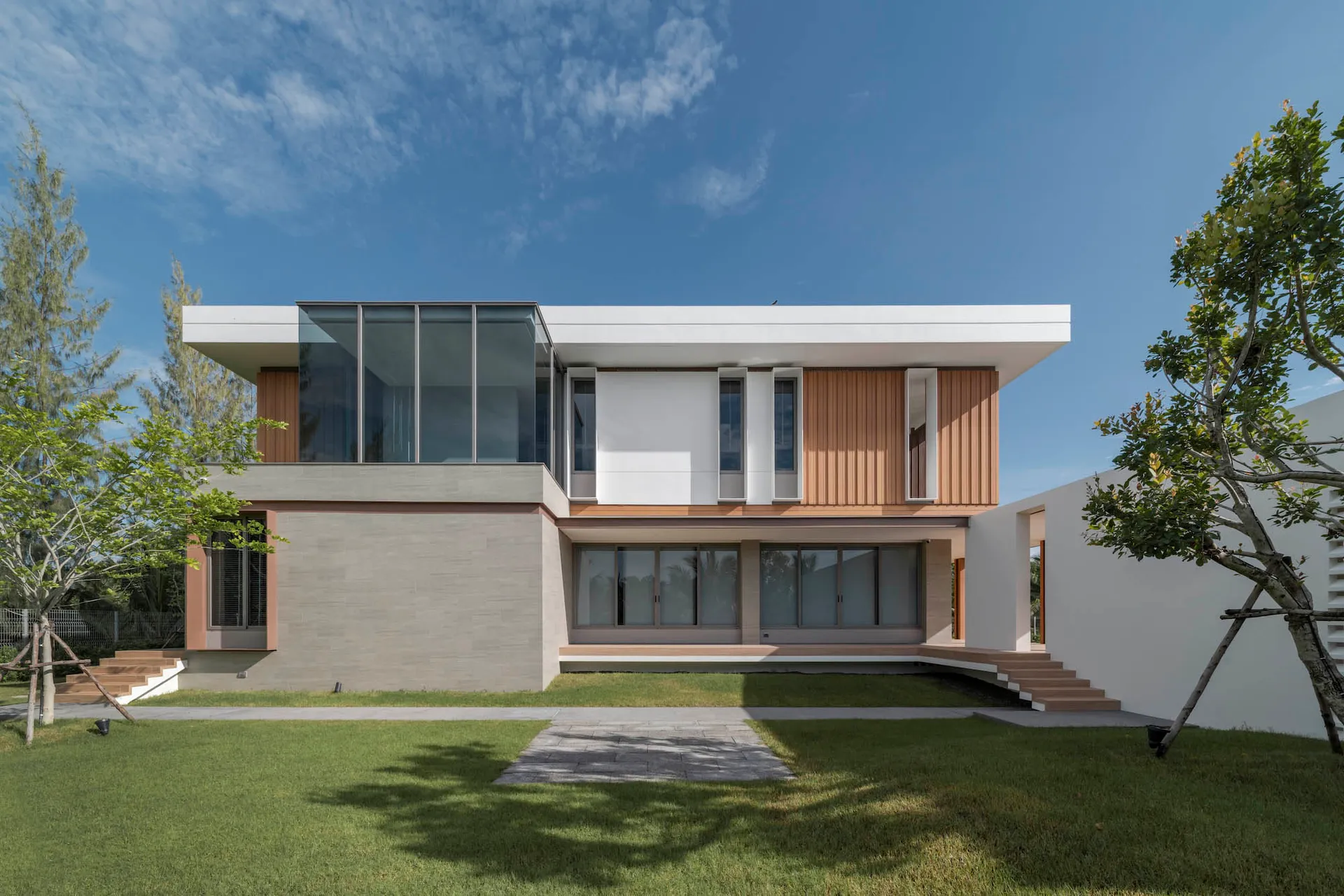 A modern residential building featuring glass, timber, and concrete materials.