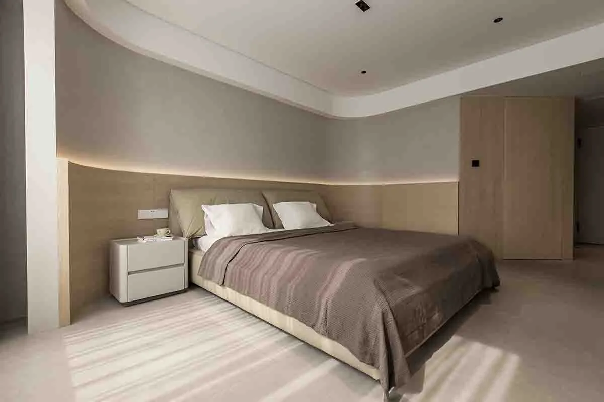 A modern bedroom with neutral-toned furniture and a minimalist design.