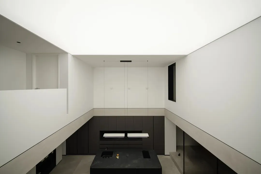 Modern minimalist kitchen with concrete elements, featuring sleek black appliances and a central island with a dark counterto